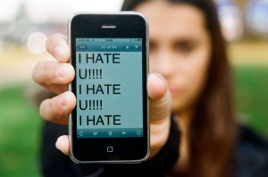 Image of girl holding cell phone with "I hate you" message